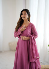 Woman wearing a pink traditional outfit with intricate detailing in a bright room.